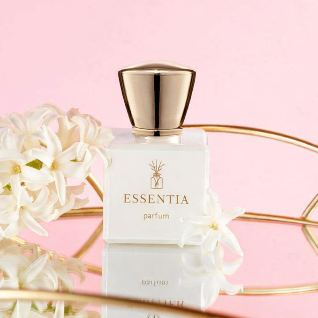 Essentia parfum bottle with gold cap surrounded by white flowers reflecting floral fragrance essence