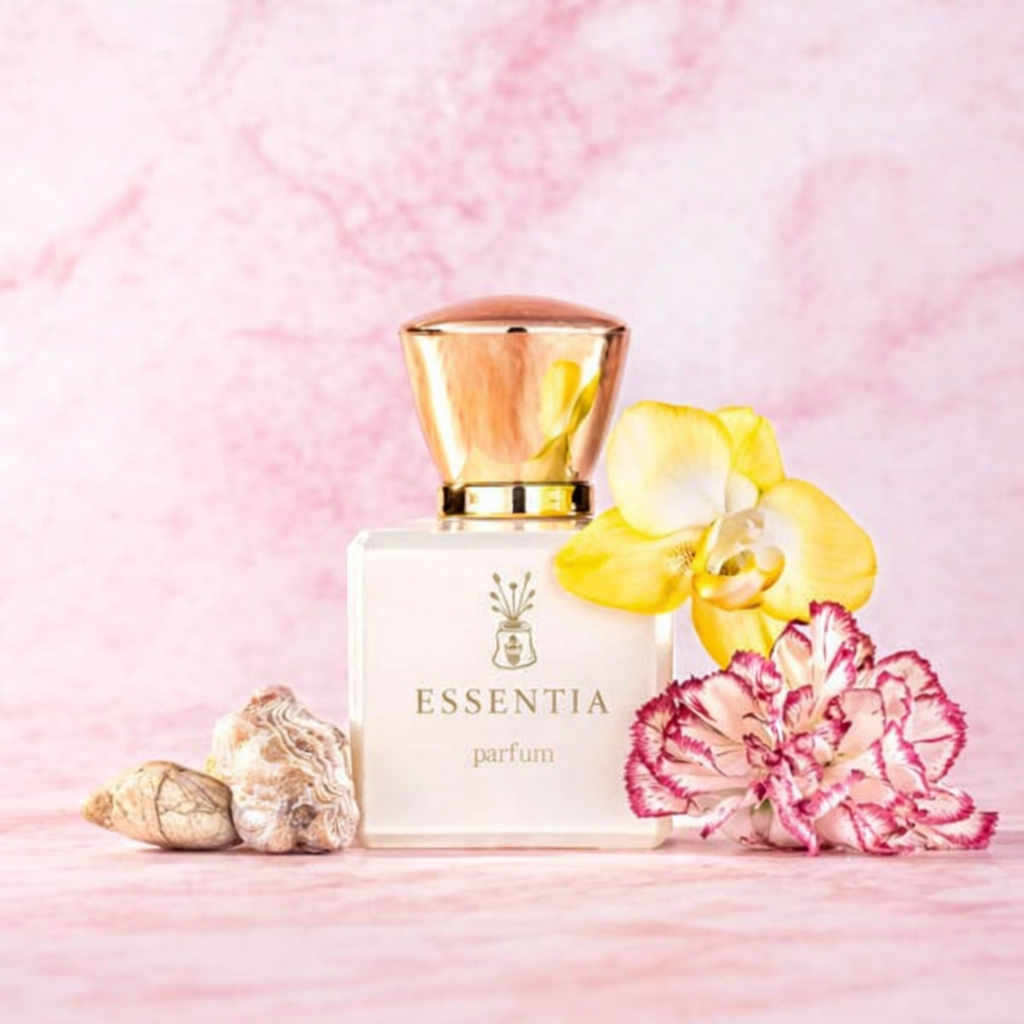 Essentia parfum bottle with floral fragrance surrounded by yellow and pink flowers on pink background